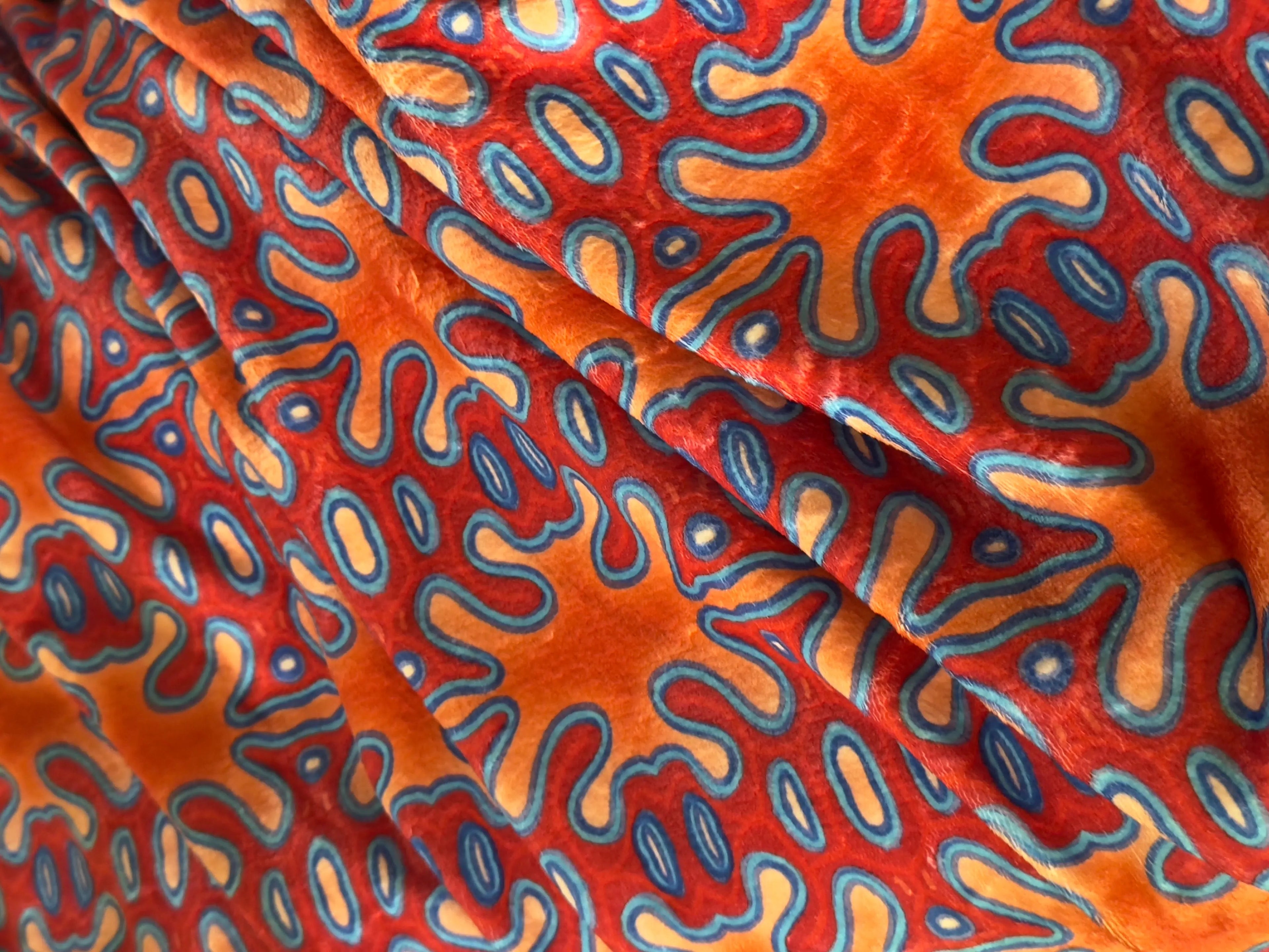 Close-up of vibrant fabric with orange and blue abstract pattern